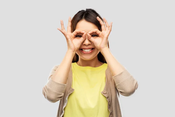 Lächelnde asiatische Frau, die durch eine Fingerbrille schaut — Stockfoto