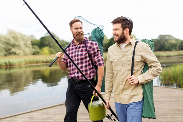 Amigos masculinos com rede e varas de pesca no lago — Fotografia de Stock