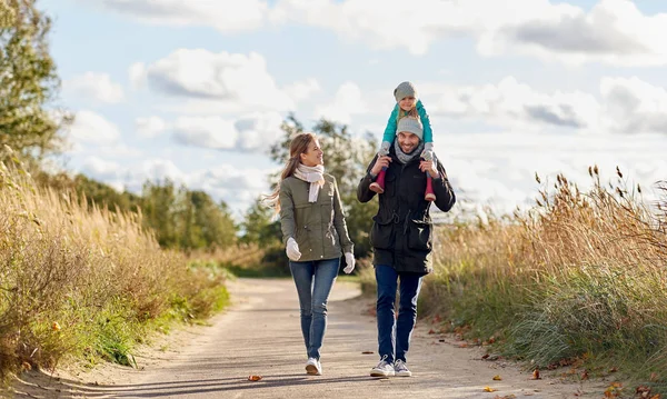 Familia feliz caminando a lo largo de camino de otoño —  Fotos de Stock