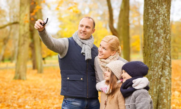 Família feliz com câmera no parque de outono — Fotografia de Stock