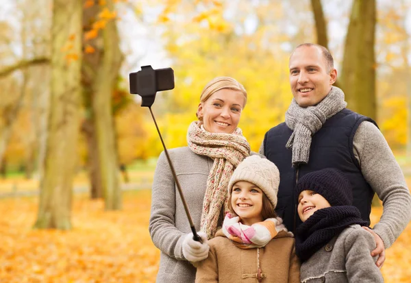 Família feliz com smartphone e monopod no parque Imagens De Bancos De Imagens Sem Royalties