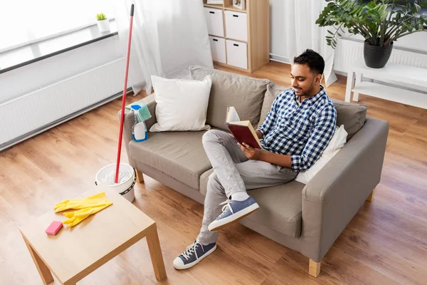 Hombre leyendo libro y descansando después de la limpieza del hogar — Foto de Stock