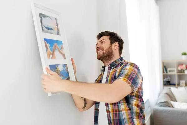 Hombre colgando imagen en el marco a la pared en casa —  Fotos de Stock