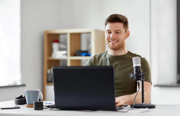 Человек с ноутбуком и микрофоном в домашнем офисе — стоковое фото