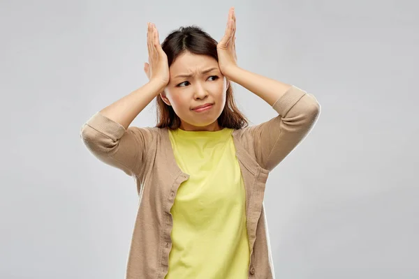 Напряженная азиатская женщина, держащаяся за голову — стоковое фото