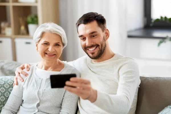 Senior moeder met volwassen zoon nemen selfie thuis — Stockfoto