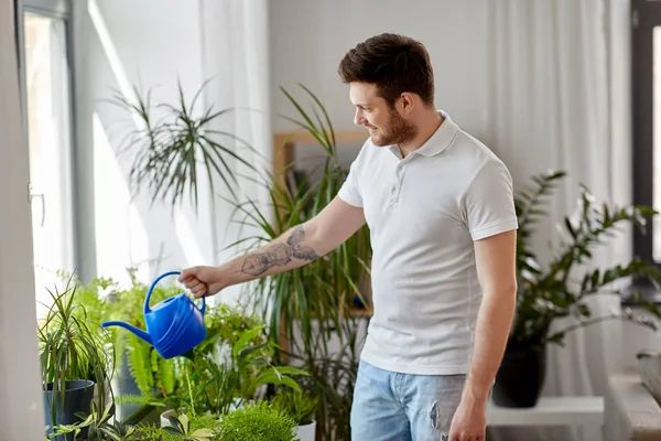 Muž zalévání pokojové rostliny doma — Stock fotografie