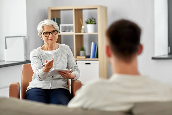 Senior vrouw psycholoog en jonge man patiënt — Stockfoto