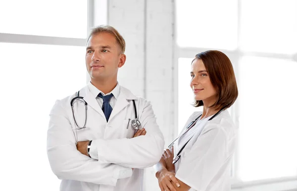 Smiling doctors in white coats at hospital — Stock Photo, Image
