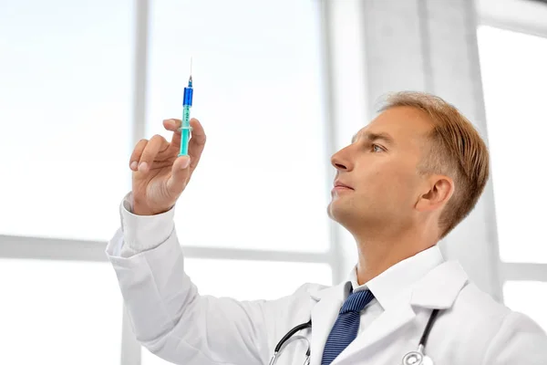 Улыбающийся доктор со шприцем в больнице — стоковое фото