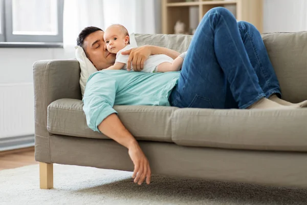 自宅でソファで寝ている赤ちゃんを持つ父親 — ストック写真