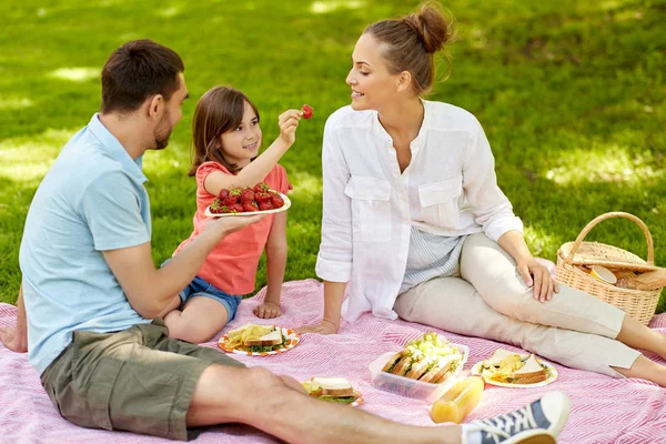 Сім'я їсть полуницю на пікніку в парку — стокове фото