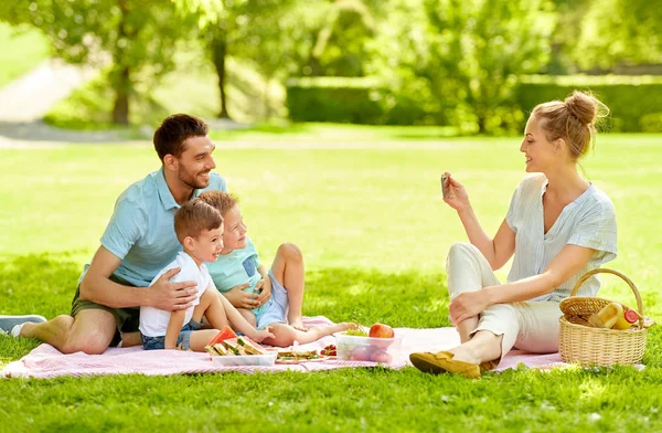 Madre tomando fotos de la familia en el picnic en el parque —  Fotos de Stock