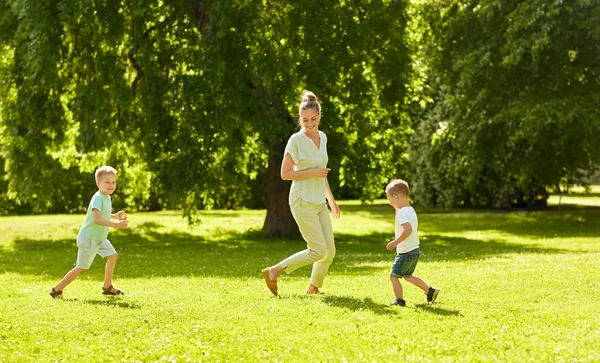 Moeder met zonen spelen catch game in zomerpark — Stockfoto