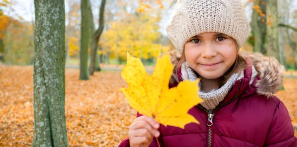 Happy girl with fallen maple leaf at autumn park — Stock Photo, Image