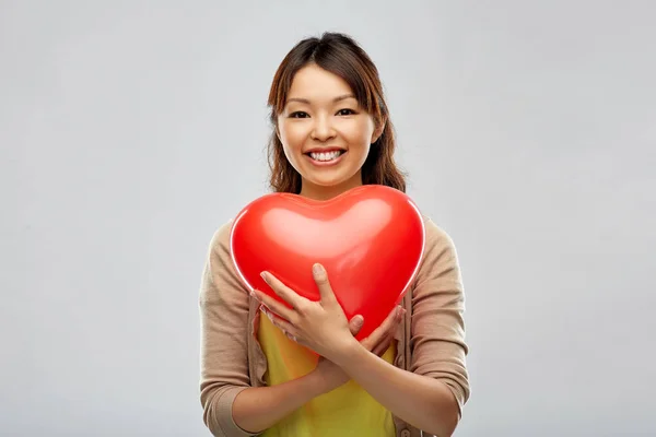 Glückliche asiatische Frau mit rotem herzförmigen Ballon — Stockfoto