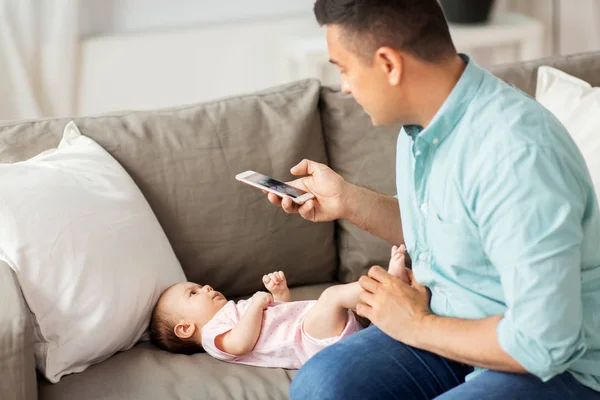 Padre con smartphone scattare foto bambino a casa — Foto Stock
