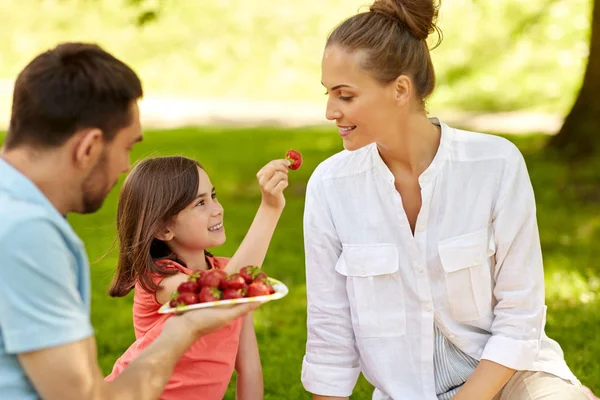 Familie eten aardbeien op picknick in Park — Stockfoto