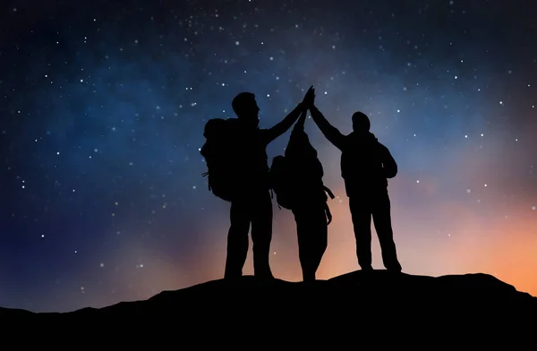 Viajantes fazendo alta cinco sobre céu estrelado noite — Fotografia de Stock