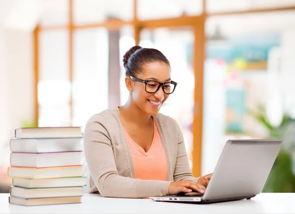 Estudiante femenina con ordenador portátil y libros — Foto de Stock