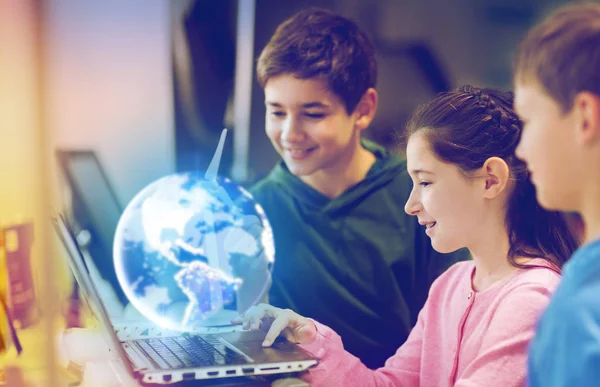 Dizüstü bilgisayar ve dünya gezegenhologramı olan çocuklar — Stok fotoğraf