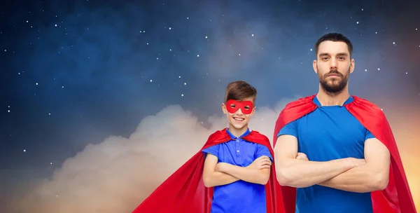 Padre e hijo en capas de superhéroes sobre el cielo nocturno — Foto de Stock
