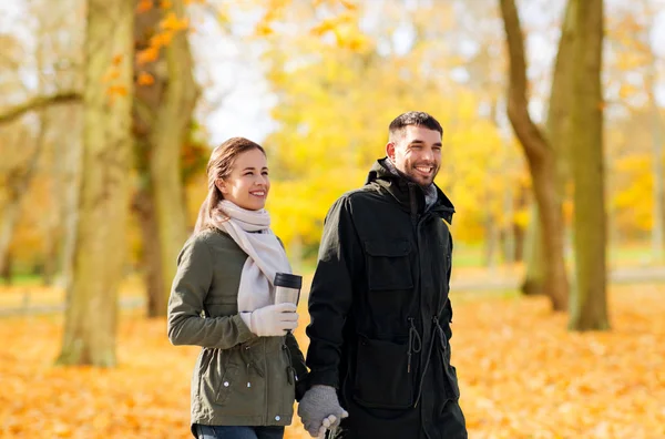 Casal com tumbler andando ao longo do parque de outono — Fotografia de Stock