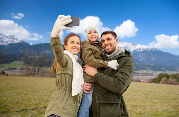 Family taking selfie by smartphone over alps — Stock Photo, Image