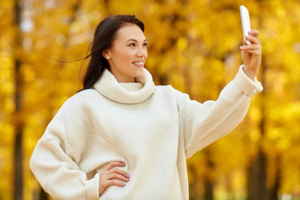 Woman taking selfie by smartphone at autumn park — Stock Photo, Image