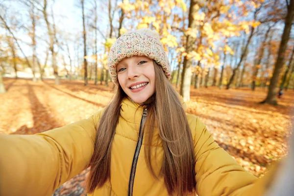 Szczęśliwy dziewczyna biorąc selfie w jesiennym parku — Zdjęcie stockowe