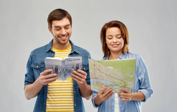 Happy couple of tourists with city guide and map — Stock Photo, Image