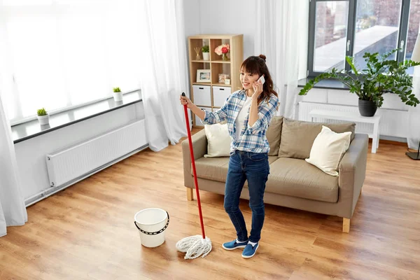 Femeie cu curățenie acasă și apelând la smartphone — Fotografie, imagine de stoc