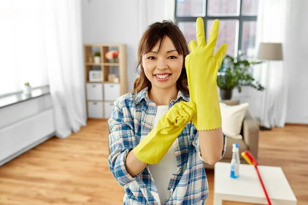 Asian woman putting protective rubber gloves on — Stock Photo, Image