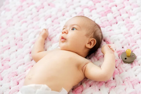Bebê menina na fralda deitado com chupeta no cobertor — Fotografia de Stock