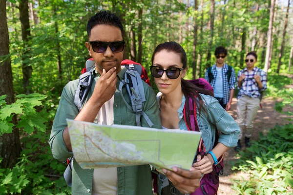 Amis avec carte et sacs à dos randonnée en forêt — Photo