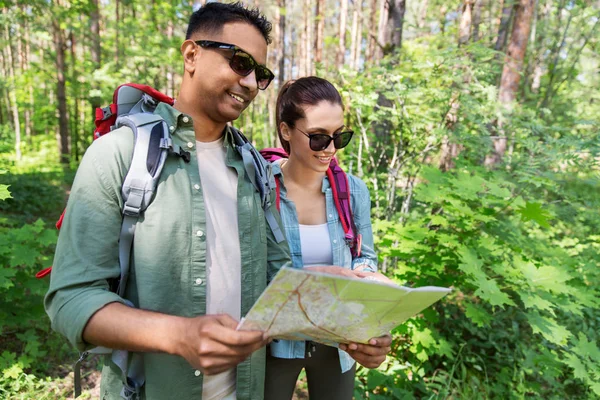 Ormanda harita ve sırt çantaları ile karışık ırk çift — Stok fotoğraf