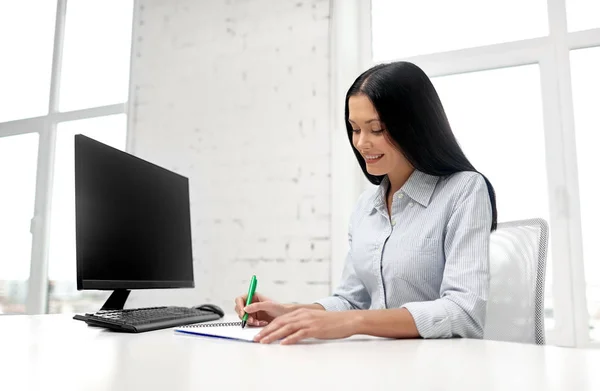 Affärskvinna skriva till anteckningsbok på kontoret — Stockfoto