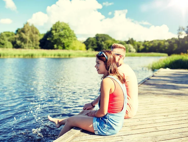 Heureux adolescent couple assis sur rivière couchette — Photo