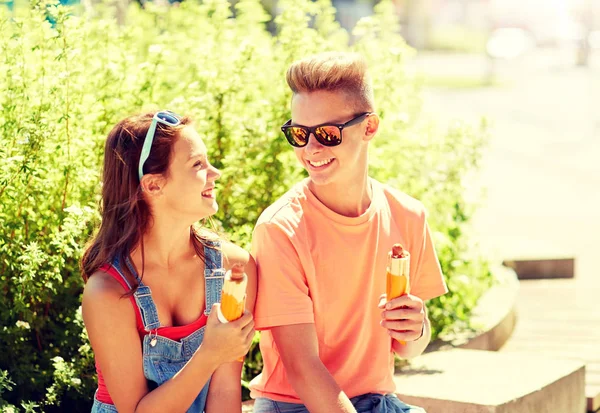 Happy teenage couple eating hot dogs in city — Stock Photo, Image