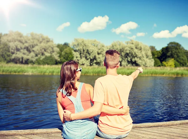 Szczęśliwa para palcem wskazującym na nabrzeżu rzeki lato — Zdjęcie stockowe