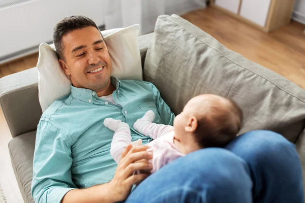 Evde kanepede yatan bebek ile orta yaşlı baba — Stok fotoğraf