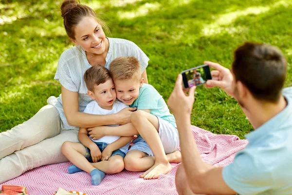 Father taking picture of family on picnic at park — Stock Photo, Image