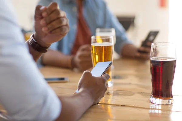 Man with smartphone drinking beer at bar or pub — Stock Photo, Image