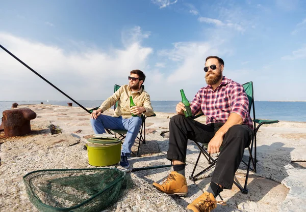 Amigos do sexo masculino pesca e beber cerveja no cais do mar — Fotografia de Stock
