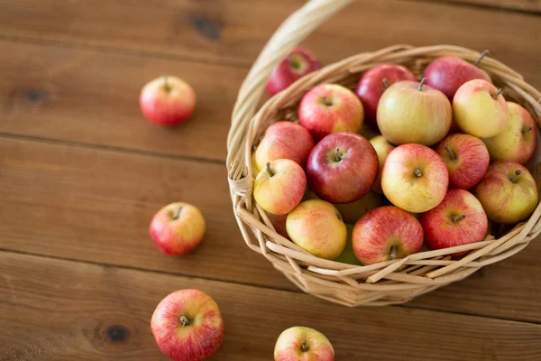 Manzanas maduras en canasta de mimbre sobre mesa de madera — Foto de Stock