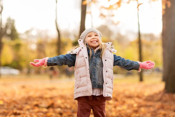 Bambina felice a braccia aperte al parco autunnale — Foto Stock