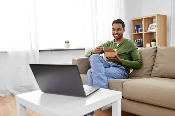 Indiana homem com laptop comer comida takeout em casa — Fotografia de Stock