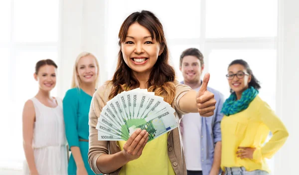 Asiático mujer con dinero mostrando pulgares arriba —  Fotos de Stock