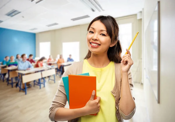 Asian female teacher with books at school — Stock Photo, Image