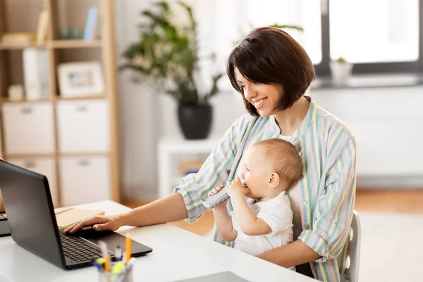 Работающая мать с маленьким мальчиком и ноутбуком дома — стоковое фото